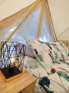 a bed with a lantern on a table next to a window at Glamping at Zeehan Bush Camp in Zeehan