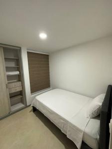 ein Schlafzimmer mit einem weißen Bett und einem Schrank in der Unterkunft Moderno Apartamento con 3 habitaciones in Dosquebradas