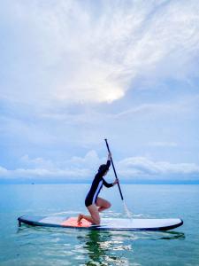 uma mulher está segurando um remo em uma prancha de surf na água em VarietyD-DayHostel HuaHin em Hua Hin