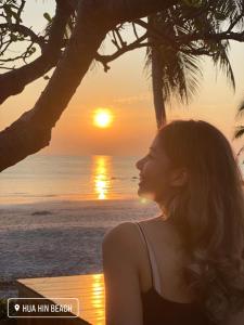 a woman sitting on the beach watching the sunset at VarietyD-DayHostel HuaHin in Hua Hin