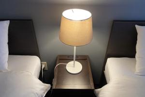 une lampe assise sur une table entre deux lits dans l'établissement WALLABY HOUSE - Vacation STAY 38649v, à Kawaguchi