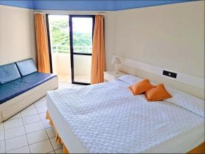 um quarto com uma cama, um sofá e uma janela em Pé na Areia em Floripa em Florianópolis