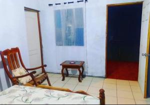 um quarto com uma cama, uma cadeira e uma mesa em Rustic House Hostel em Moyogalpa