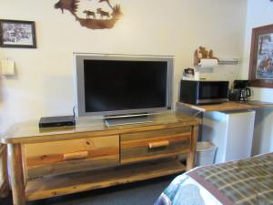 einen TV auf einer hölzernen Kommode in einem Schlafzimmer in der Unterkunft The Woodsman Country Lodge Motel in Crescent