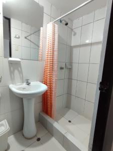 La salle de bains blanche est pourvue d'un lavabo et d'une douche. dans l'établissement CUSI QOYLLOR, à Machu Picchu