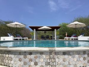a swimming pool with chairs and umbrellas at Villa San Sebastian Curaçao in Fontein