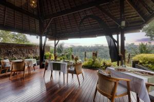 um restaurante com mesas e cadeiras num piso de madeira em Black Penny Villas Ubud em Ubud