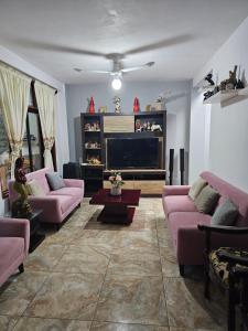 sala de estar con sofás rosados y TV de pantalla plana en Casa Yarinacocha, en Pucallpa