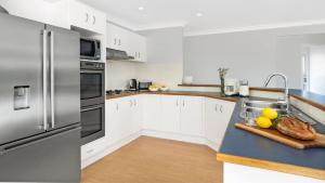a kitchen with white cabinets and a stainless steel refrigerator at Highlands on Alice in Bowral