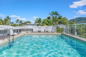 a swimming pool with two chairs and a fence at Sarayi Boutique Hotel in Palm Cove