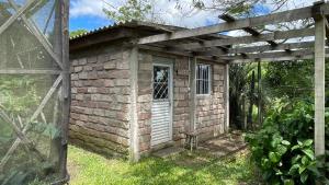 a brick building with a white door and a wooden pergola at Instituto Bugio Ruivo in Eldorado do Sul 