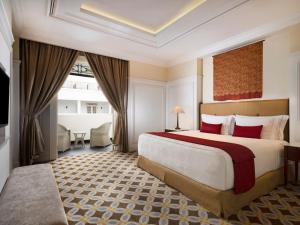 um quarto de hotel com uma cama grande e uma janela grande em The Hermitage, A Tribute Portfolio Hotel, Jakarta em Jakarta