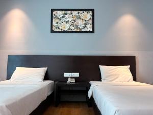twee bedden in een kamer met een foto aan de muur bij Cube Plus Signature Hotel OUG Kuala Lumpur in Kuala Lumpur