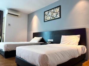 een hotelkamer met twee bedden en een foto aan de muur bij Cube Plus Signature Hotel OUG Kuala Lumpur in Kuala Lumpur