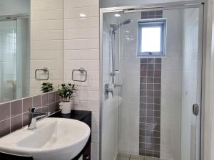 a white bathroom with a sink and a shower at Pumicestone Blue Resort in Caloundra
