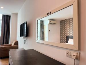 a room with a mirror and a couch and a television at Cube Plus Signature Hotel OUG Kuala Lumpur in Kuala Lumpur