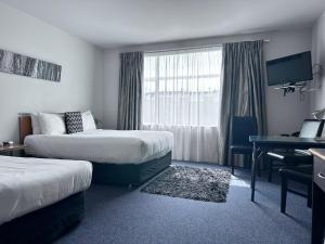 a hotel room with two beds and a desk at Best Western Wellington in Wellington