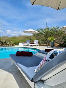 a pool with two lounge chairs and an umbrella at Villa San Sebastian Curaçao in Fontein