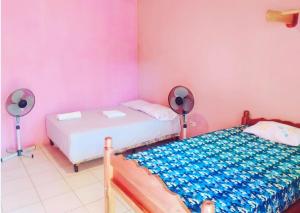 two beds in a room with pink walls and fans at Rustic House Hostel in Moyogalpa