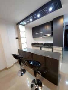 a kitchen with two black stools and a counter at Acogedor departamento en Huacachina in Ica