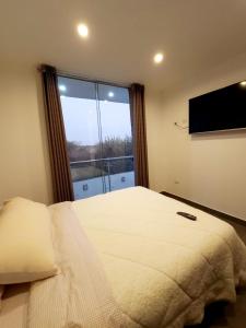 a bedroom with a bed and a large window at Acogedor departamento en Huacachina in Ica
