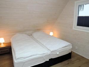 un letto bianco in una camera con parete in legno di Comfortable holiday homes for 6 people, close to the sea a Dziwnówek