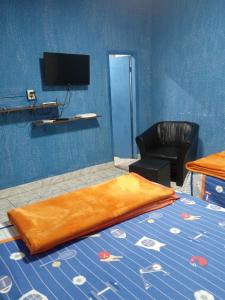 Cette chambre comprend un lit, une chaise et une télévision. dans l'établissement El Viajero Hostel & Suítes 10, à Pedro Juan Caballero