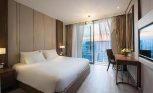 ein Hotelzimmer mit einem großen weißen Bett und einem Schreibtisch in der Unterkunft Panorama Sky Blue Nha Trang in Nha Trang