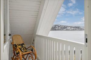 une chaise assise sur une terrasse couverte avec vue sur l'océan dans l'établissement Idyllisk hus ved sjøen, à Hammerfest