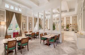 a dining room with tables and chairs and a kitchen at The Hermitage, A Tribute Portfolio Hotel, Jakarta in Jakarta