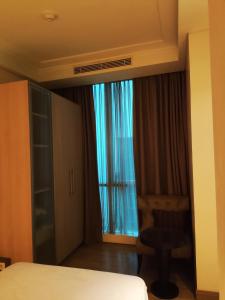 a bedroom with a bed and a chair and a window at Apartement The Peak Sudirman in Jakarta