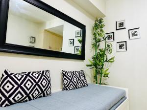 a mirror on a wall with a couch and a plant at Sea Residences - Angel Alano in Manila