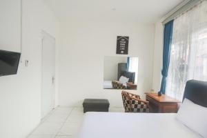 een witte kamer met een bureau en een raam bij OYO Life 3055 Rumah Enin in Bandung