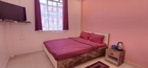 a bedroom with a bed with red sheets and a window at Tranquil Vista Homestay in Cherrapunji