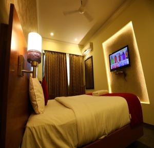 um quarto de hotel com uma cama e uma televisão de ecrã plano em DFRONT GOLDEN PALACE em Nāmakkal
