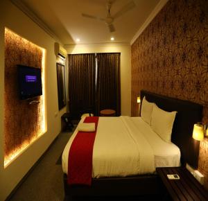 um quarto de hotel com uma cama e uma televisão em DFRONT GOLDEN PALACE em Nāmakkal