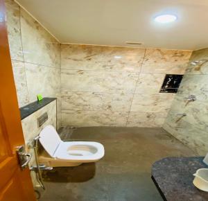 uma casa de banho com um WC e uma parede de pedra em DFRONT GOLDEN PALACE em Nāmakkal