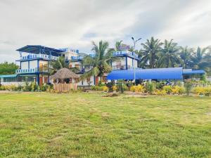 un grande edificio blu con un campo di fronte di Victory's Gardens a Mannar
