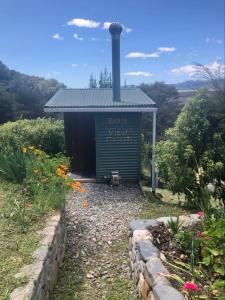 a small green building with a sign on it at First Light Rangihaeata Retreat in Takaka