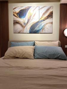 una camera da letto con tre dipinti appesi sopra un letto di Iloilo Travellers Zen Zone a Città di Iloilo