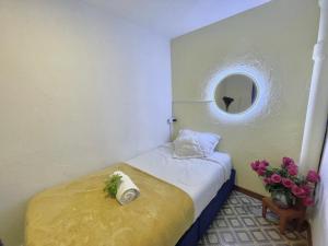 Habitación pequeña con cama y ventana redonda en Prisma Hostel, en Bogotá