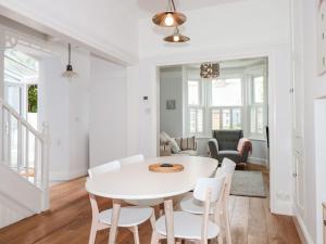 uma sala de jantar branca com uma mesa e cadeiras brancas em Bay Tree Cottage, Dartmouth em Dartmouth