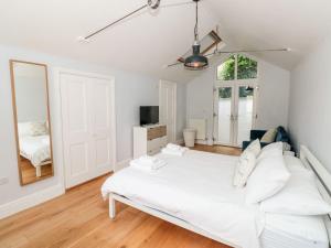 um quarto branco com uma cama e um espelho em Bay Tree Cottage, Dartmouth em Dartmouth