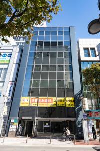 um edifício alto com pessoas a andar na frente dele em 脈 -MYAKU PRIVATE SAUNA- em Fukuoka