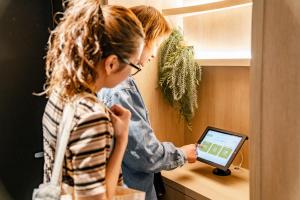 a woman is looking at a tablet in a shelf at 脈 -MYAKU PRIVATE SAUNA- in Fukuoka