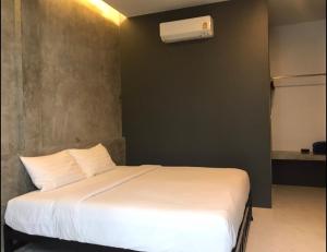 1 dormitorio con 1 cama blanca y aire acondicionado en NemoCottage, en Ban Khlong Haeng