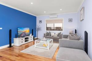 un salon avec un canapé et une télévision dans l'établissement Nelson Bay Aqua Haven, à Nelson Bay