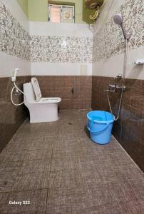 a bathroom with a toilet and a blue bucket at RUSHITHA HOME STAY-AC Rooms-FREE WIFI-FLAT TV- KITCHEN-DOOR SERVICE-NEAR TO ALIPIRI in Tirupati
