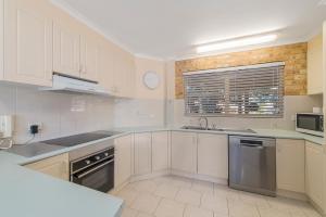 a kitchen with white cabinets and a sink at Ocean Shores Apartment 2 in South West Rocks