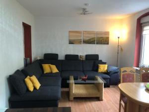 a living room with a blue couch and yellow pillows at Haus am Wald in Hohndorf +1 photo